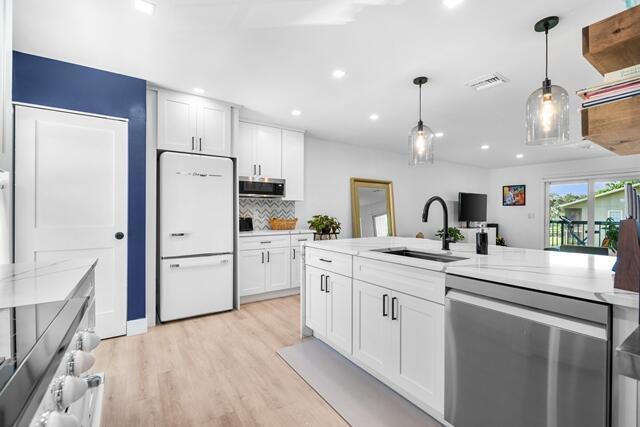 A modern kitchen features white cabinetry, a retro-style refrigerator, and a large marble-topped island — 18460 SE Wood Haven Lane # H, Jupiter FL 33469, JUPITER, FL