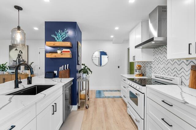 A modern kitchen features white cabinets, marble-look countertops, a blue accent wall, and wood flooring — 18460 SE Wood Haven Lane # H, Jupiter FL 33469, JUPITER, FL