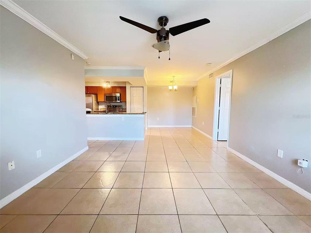 An open-concept living area with light tile flooring, a ceiling fan, and an adjacent kitchen — 3008 PARKWAY BOULEVARD UNIT 306, KISSIMMEE, FL