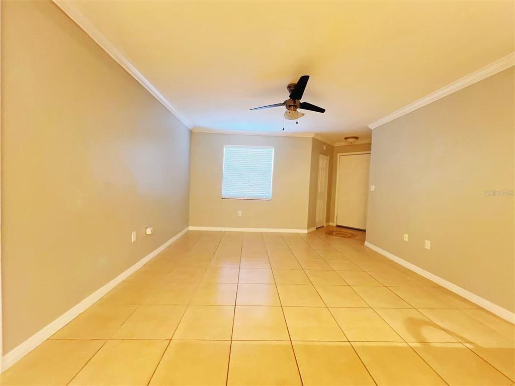 An empty room with light-colored tile flooring, beige walls, and a ceiling fan — 3008 PARKWAY BOULEVARD UNIT 306, KISSIMMEE, FL