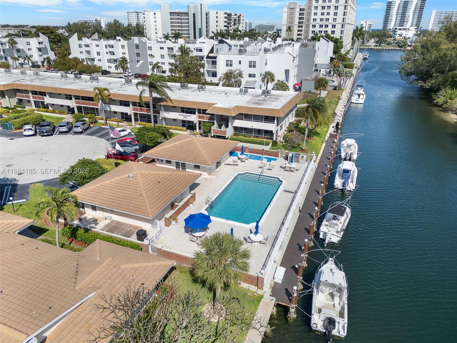 An aerial view shows a swimming pool, clubhouse, and boat docks along a canal — 1340 NE 28th Ave # 244, Pompano Beach FL 33062, POMPANO BEACH, FL