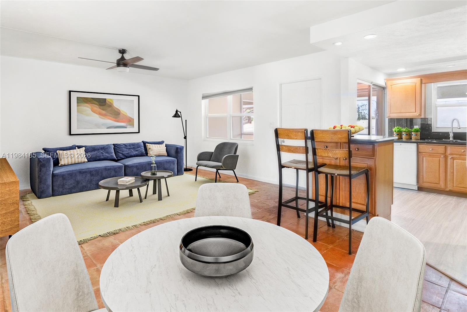 An open-concept living and dining area features a blue sofa, kitchen island, and tiled floors — 1340 NE 28th Ave # 244, Pompano Beach FL 33062, POMPANO BEACH, FL