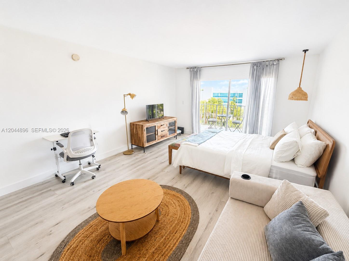 A studio apartment features a bed, a sofa, a desk, and a balcony with outdoor seating — 650 NE 64 ST # G506, Miami FL 33138, MIAMI, FL