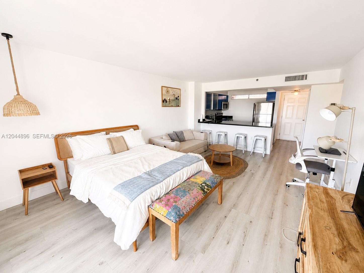 A studio apartment features a bed, small living area, kitchen, and desk on light flooring — 650 NE 64 ST # G506, Miami FL 33138, MIAMI, FL