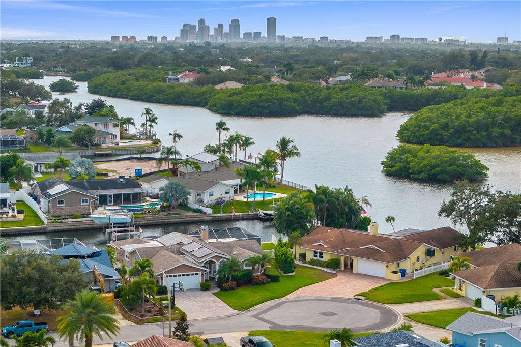 An aerial view shows waterfront houses with pools and docks along a bay near a city — 1320 52ND AVENUE NE, ST PETERSBURG, FL