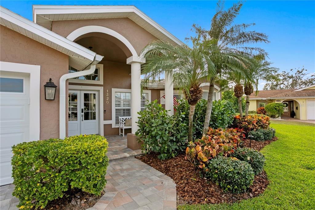 A paved walkway leads to the front entrance of a house with a palm tree — 1320 52ND AVENUE NE, ST PETERSBURG, FL