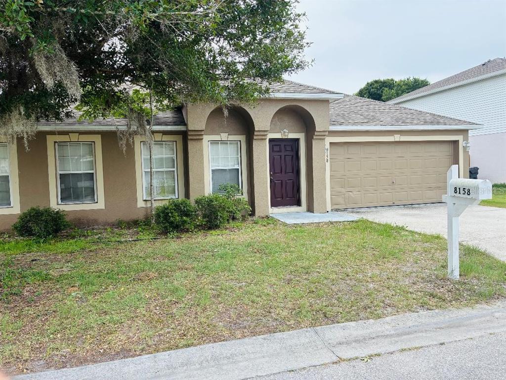 A single-story house with a brown exterior, arched entryway, and an attached two-car garage — 8158 SETTLERS CREEK CIRCLE, LAKELAND, FL