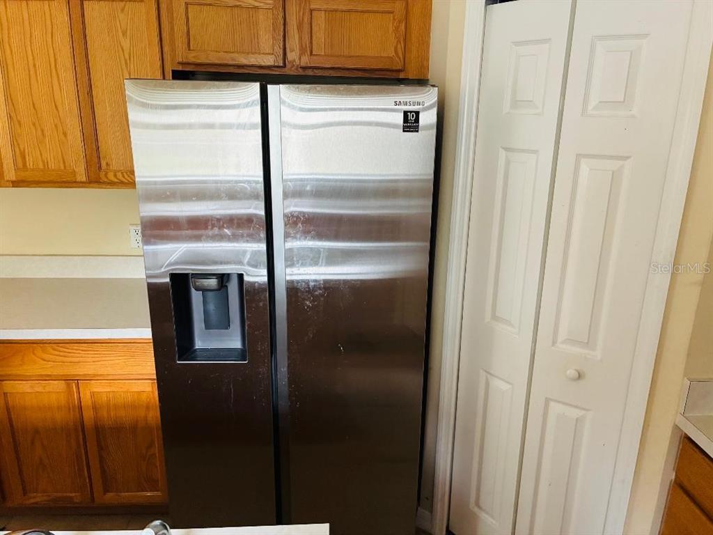 A stainless steel Samsung side-by-side refrigerator stands in a kitchen with wooden cabinets — 8158 SETTLERS CREEK CIRCLE, LAKELAND, FL