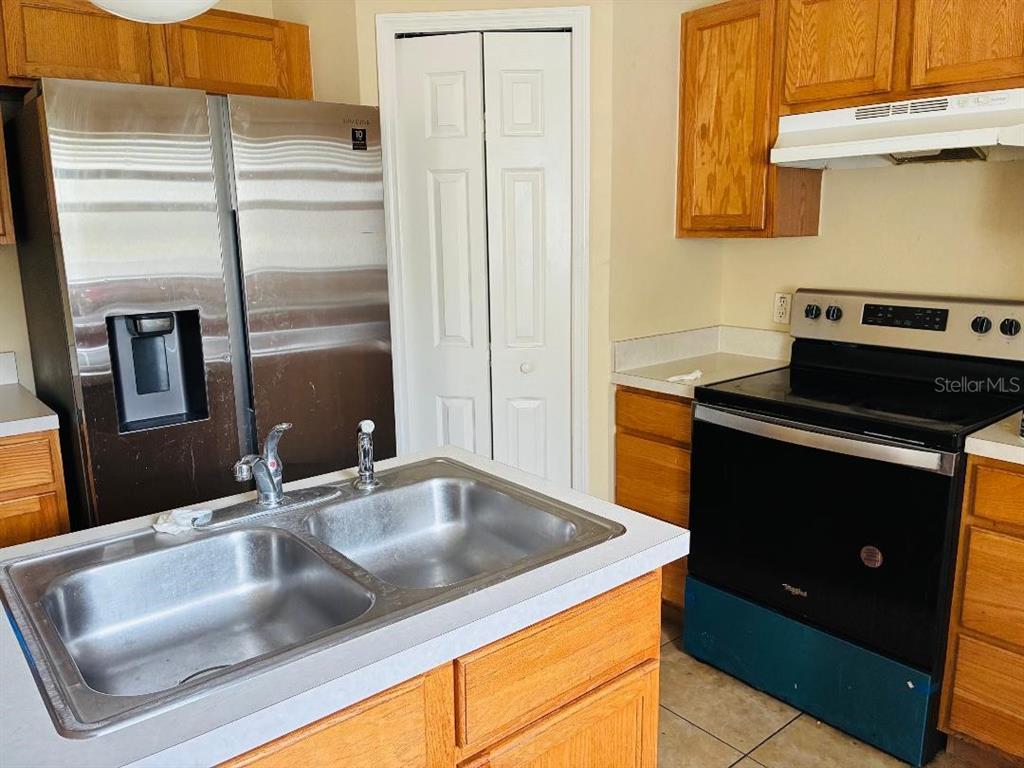 A kitchen featuring a stainless steel refrigerator, a black stove, and a double-basin sink — 8158 SETTLERS CREEK CIRCLE, LAKELAND, FL