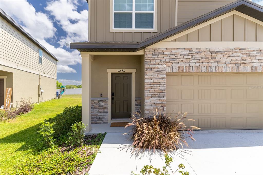 The exterior of a two-story house features a stone facade, a garage, and a front door — 8688 SPORTSMAN LOOP, GROVELAND, FL