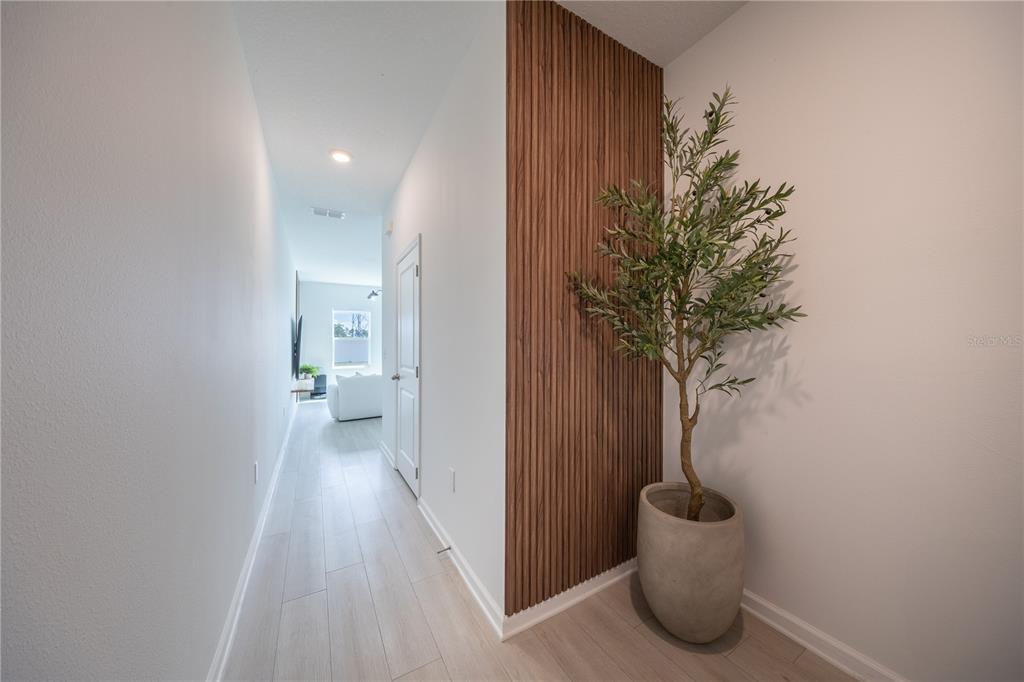 A hallway features light wood flooring, a white door, and a vertical wood slat accent wall — 8688 SPORTSMAN LOOP, GROVELAND, FL