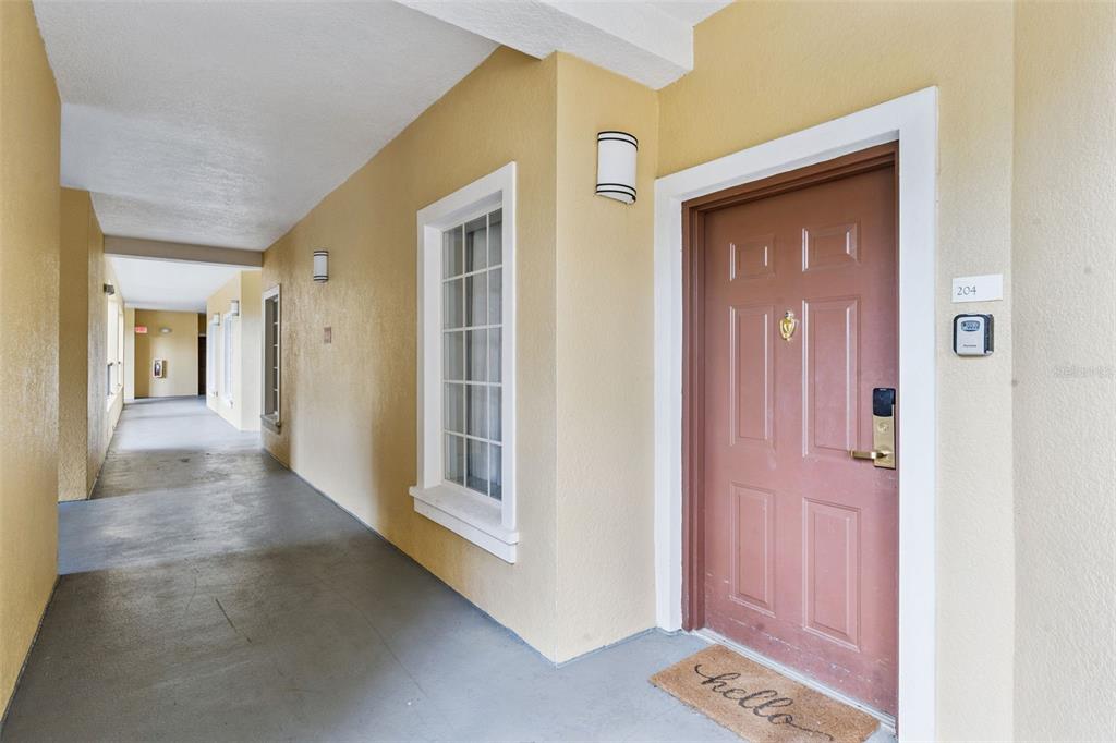 A brown front door with a keypad lock sits at the end of a hallway — 8774 WORLDQUEST BOULEVARD UNIT 7204, ORLANDO, FL