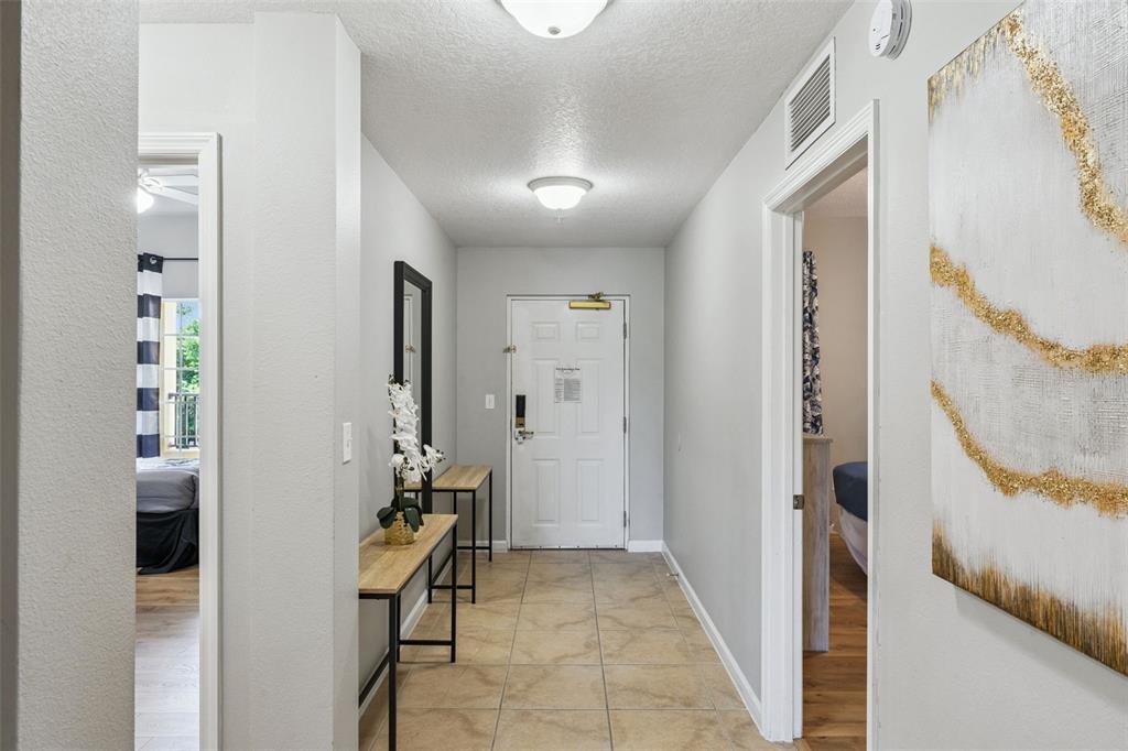 A tiled entryway features a white front door, two console tables, and two doorways — 8774 WORLDQUEST BOULEVARD UNIT 7204, ORLANDO, FL