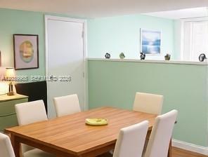A dining room with a wooden table, white chairs, and a half-wall partition — 3930 S Roosevelt Blvd # 0, Key West FL 33040, KEY WEST, FL