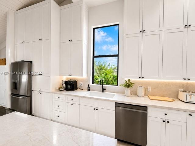 A modern kitchen features white cabinetry, stainless steel appliances, and a window above the sink — 2641 S Parkview Dr, Hallandale Beach FL 33009, HALLANDALE BEACH, FL