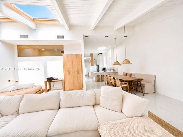 A modern white kitchen features a large island, wooden range hood, and light tile flooring — 2641 S Parkview Dr, Hallandale Beach FL 33009, HALLANDALE BEACH, FL