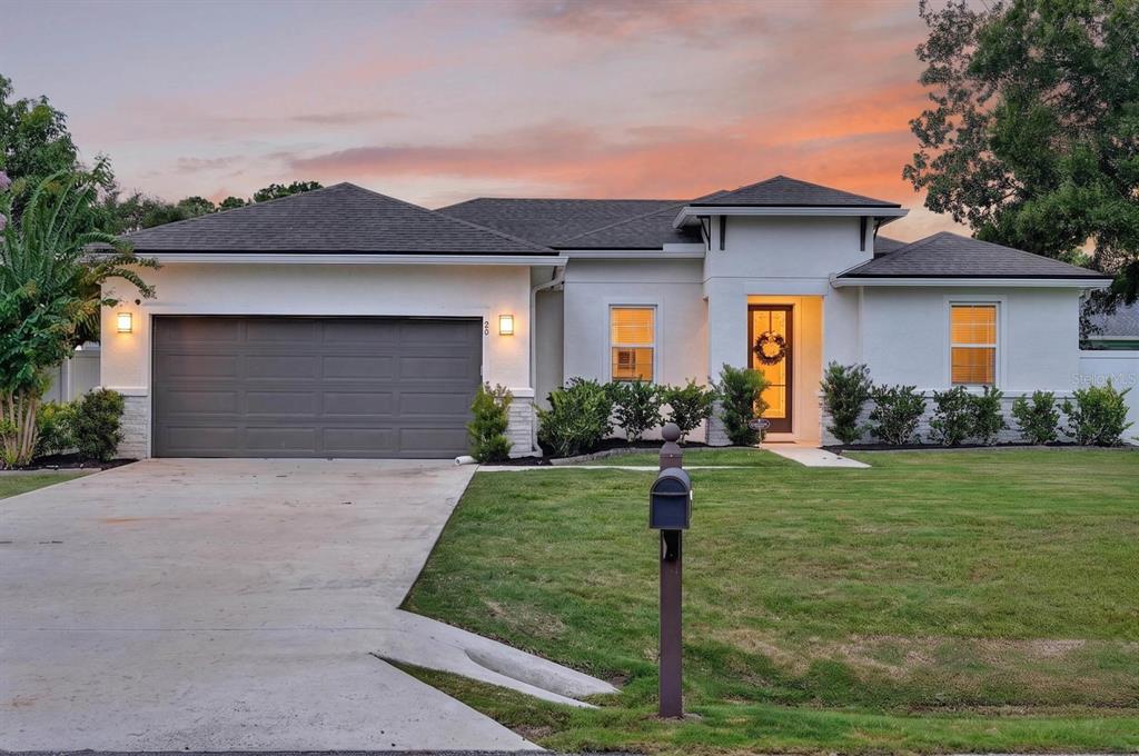 A single-story house with a white stucco exterior, dark roof, and a two-car garage — 20 PICKCANE LANE, PALM COAST, FL