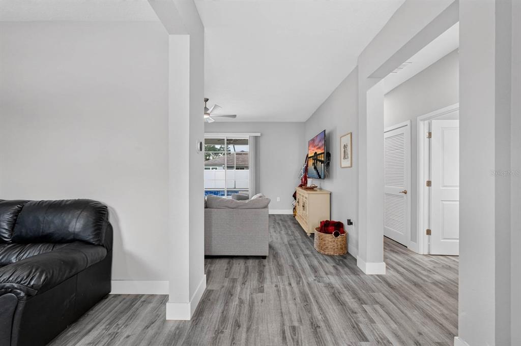 A view from a hallway into a living room with gray flooring and a pool view — 20 PICKCANE LANE, PALM COAST, FL
