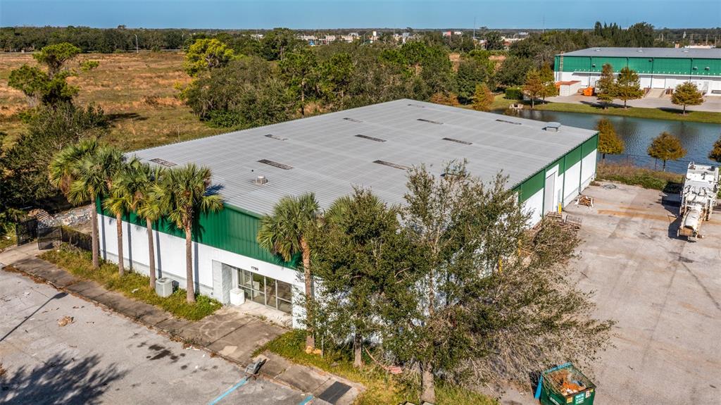 An aerial view shows a large warehouse building with a metal roof and palm trees — 1770 BUSINESS CENTER LANE, KISSIMMEE, FL