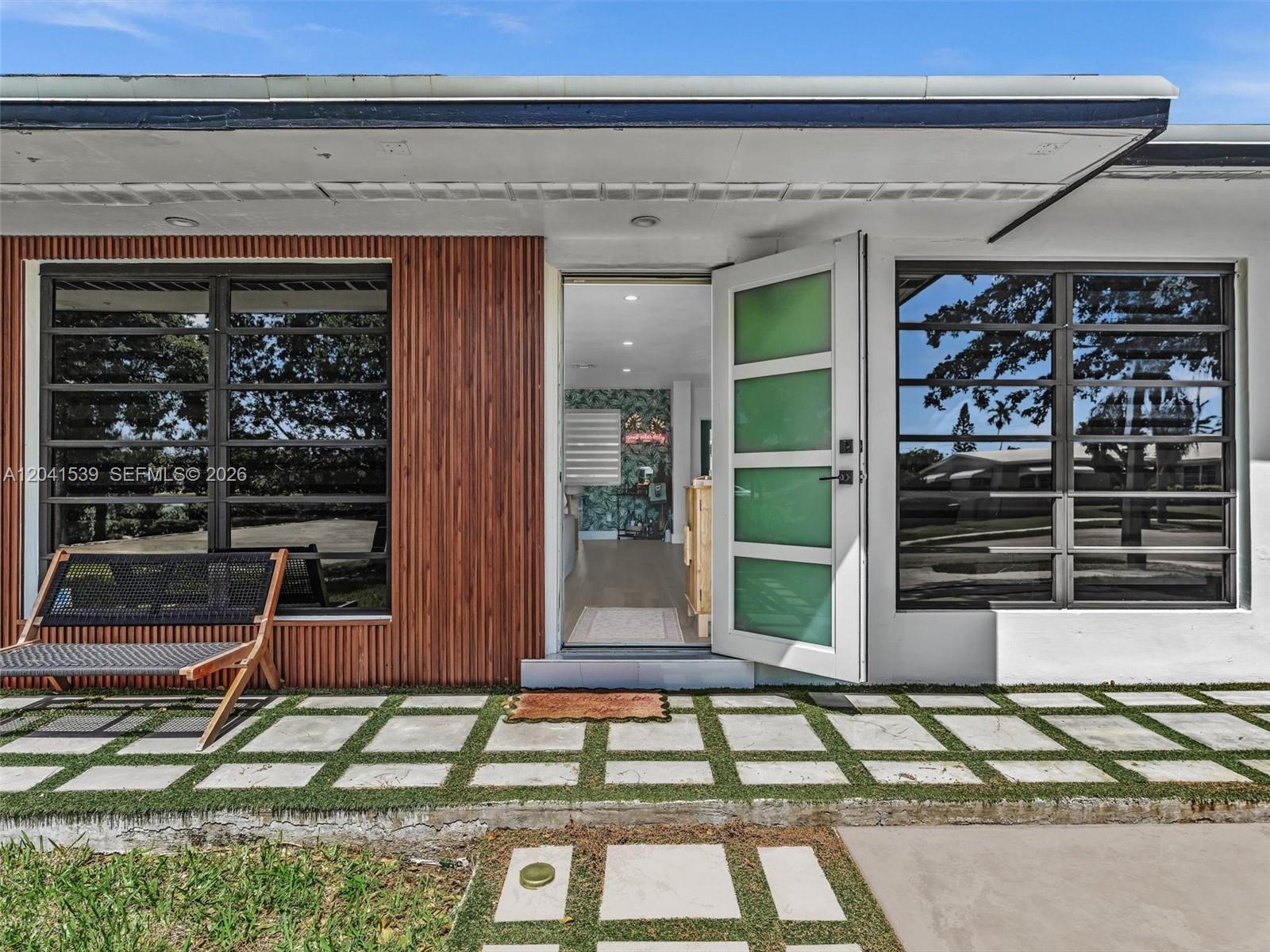 The exterior of a modern home features a slatted wood wall, glass-paneled door, and pavers — 20210 SW 106th Ct, Cutler Bay FL 33189, CUTLER BAY, FL