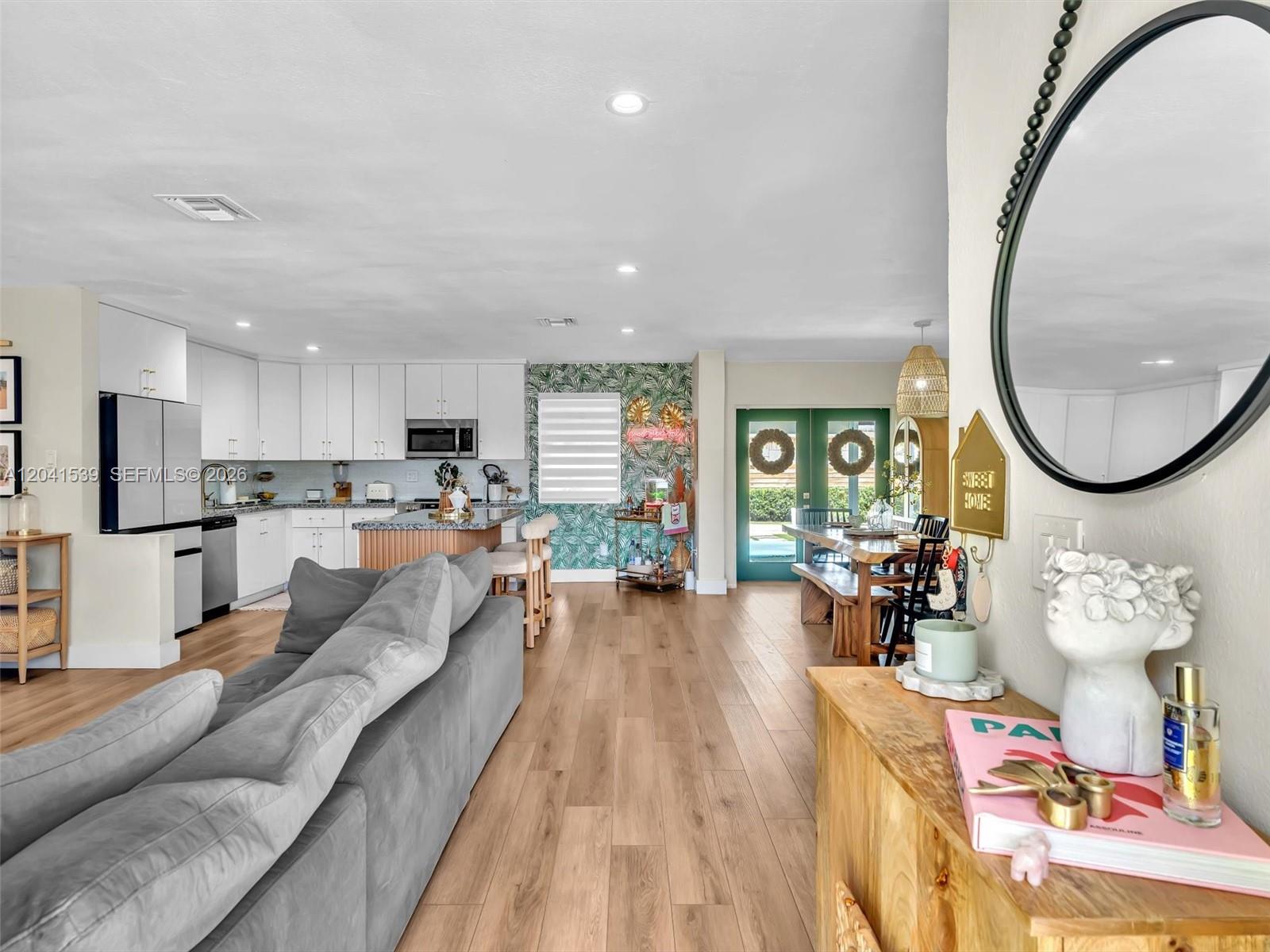 An open-concept kitchen, dining area, and living room feature light wood flooring and white cabinetry — 20210 SW 106th Ct, Cutler Bay FL 33189, CUTLER BAY, FL