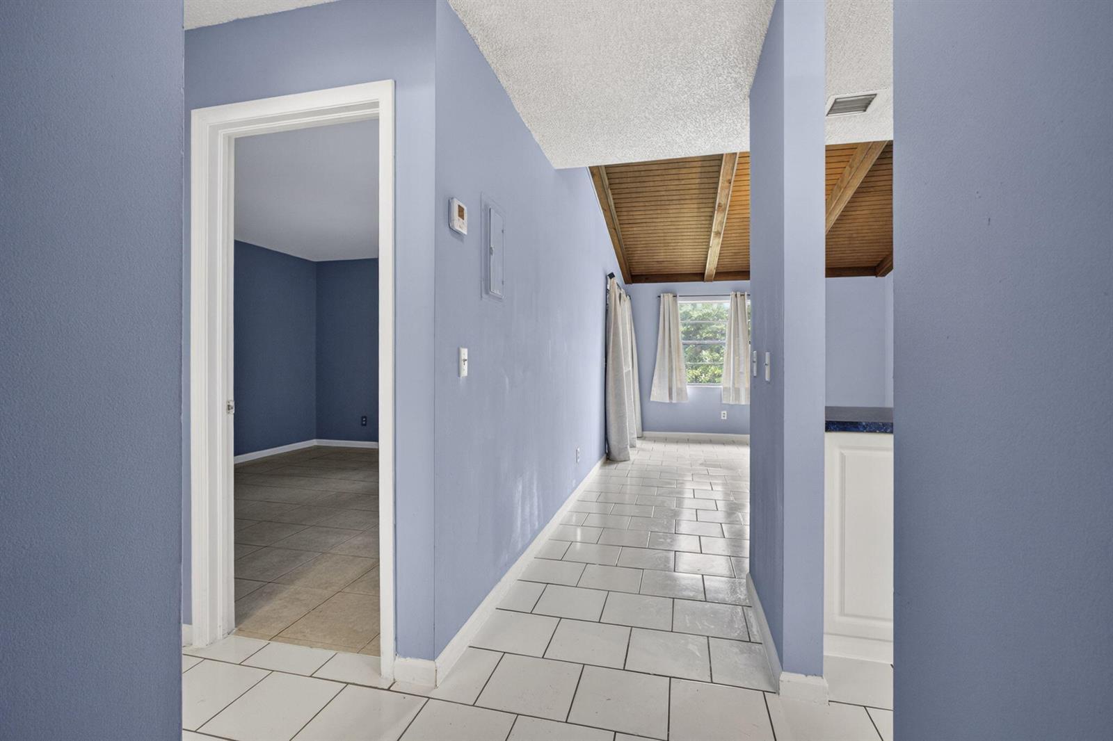 A hallway with white tile floors leads toward a room with a vaulted wood ceiling — 4661 Perth Road # 4661, West Palm Beach FL 33415, WEST PALM BEACH, FL