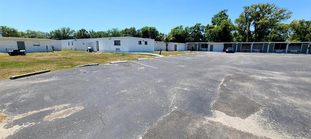 A large asphalt parking lot sits in front of a long, single-story white motel building — 421 E KENNEDY BOULEVARD, EATONVILLE, FL