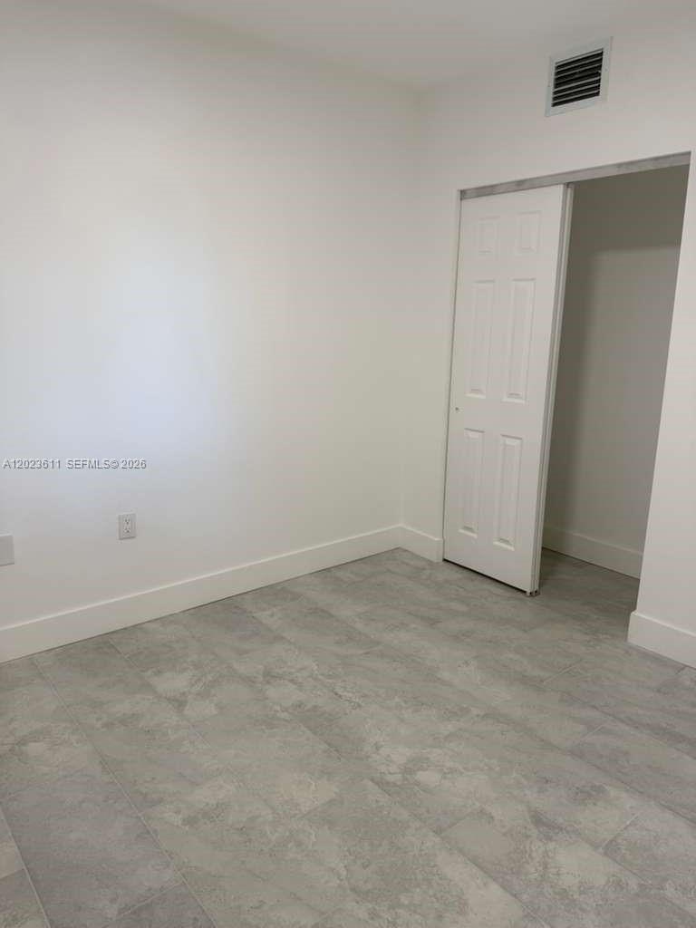 A small room features white walls, gray tile flooring, and a white sliding closet door — 147 Nw 59th St # 204, Miami FL 33127, MIAMI, FL