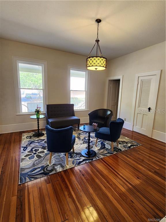 A living room features hardwood floors, a patterned area rug, four chairs, and a chandelier — 101 S OSCEOLA AVENUE, INVERNESS, FL