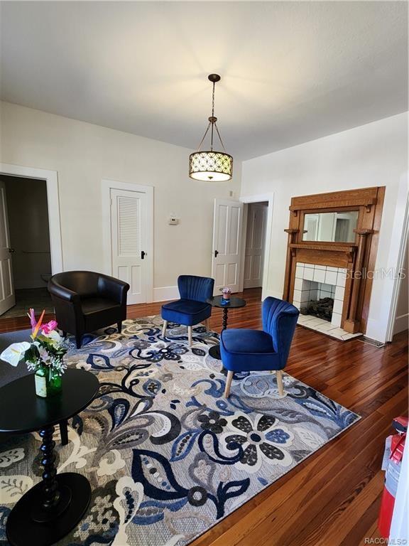 A living room features a fireplace, hardwood floors, a patterned rug, and several chairs — 101 S OSCEOLA AVENUE, INVERNESS, FL