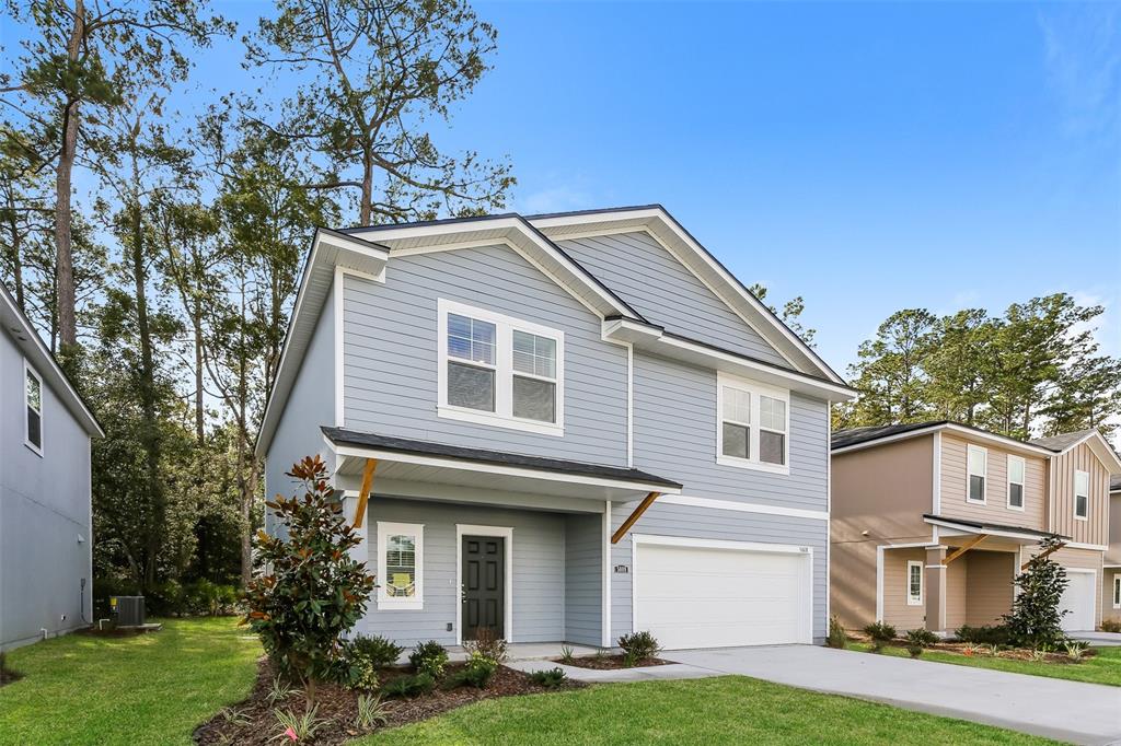 A two-story light blue house with a front-facing garage and a small covered entryway — 5008 BRAMANTE DRIVE, JACKSONVILLE, FL