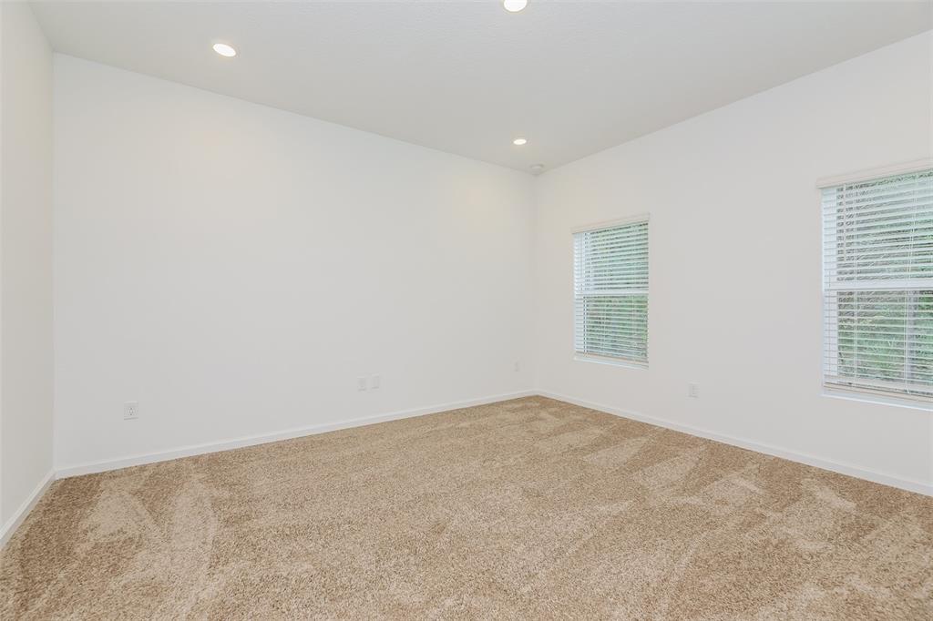 An empty bedroom features white walls, tan carpet, and two windows with white blinds — 5008 BRAMANTE DRIVE, JACKSONVILLE, FL