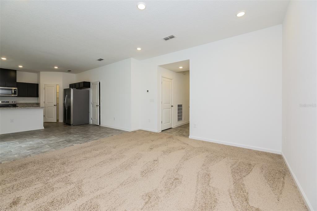 A carpeted living area opens to a kitchen with dark cabinets and tile flooring — 5008 BRAMANTE DRIVE, JACKSONVILLE, FL