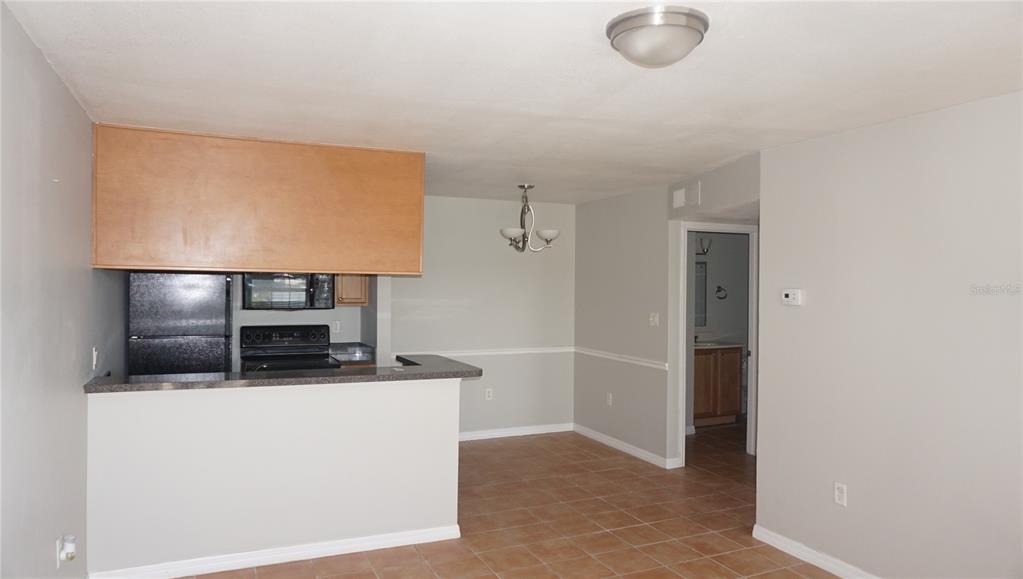 A kitchen with a breakfast bar, black appliances, and a dining area with tile flooring — 220 LAKE PARSONS GREEN UNIT 206, BRANDON, FL
