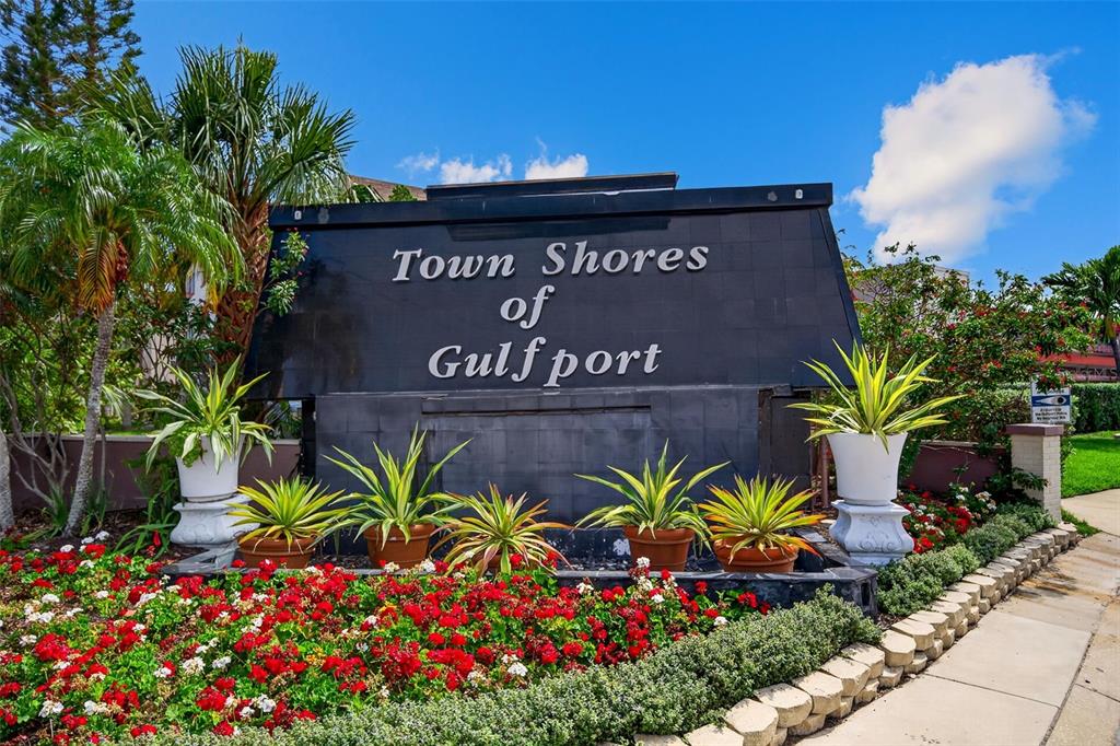 A black monument sign for Town Shores of Gulfport sits behind a bed of red flowers — 6025 SHORE BOULEVARD S UNIT 602, GULFPORT, FL