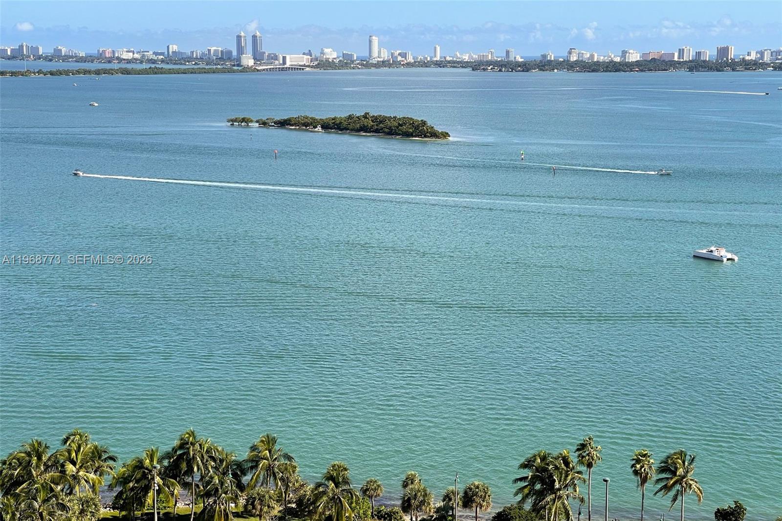 A high-angle view shows a body of water with a small island and distant skyline — 2020 N Bayshore Dr # 3102, Miami FL 33137, MIAMI, FL