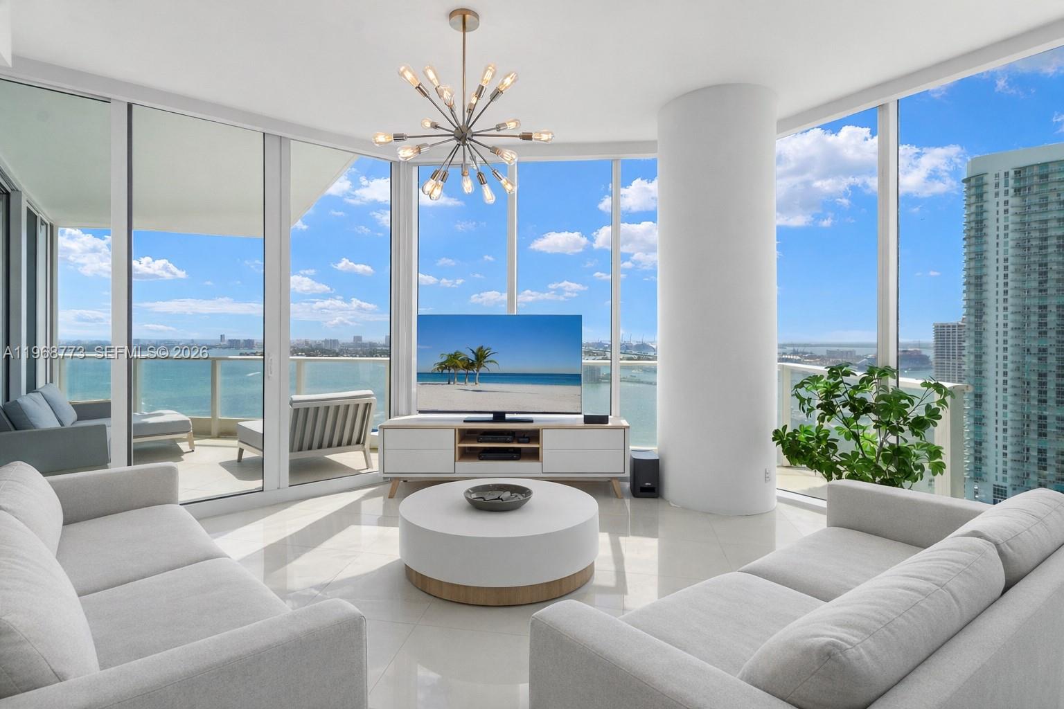 A bright living room features white sofas, a round coffee table, and floor-to-ceiling windows — 2020 N Bayshore Dr # 3102, Miami FL 33137, MIAMI, FL