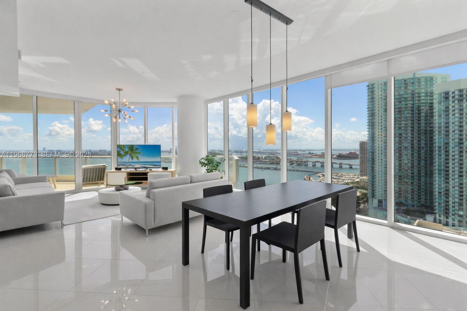 A modern living and dining area features floor-to-ceiling windows with expansive city and water views — 2020 N Bayshore Dr # 3102, Miami FL 33137, MIAMI, FL