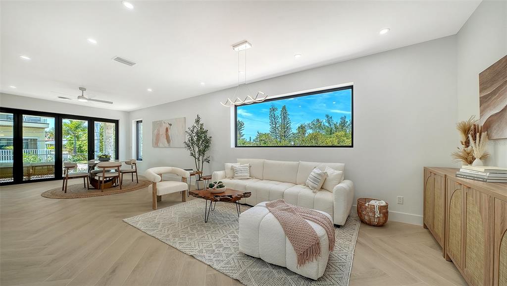 A bright living room features a white sofa, patterned rug, and large horizontal window — 2908 AVENUE B, BRADENTON BEACH, FL