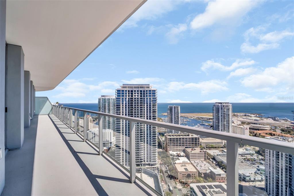 A high-rise balcony with a glass railing overlooks a city skyline and the ocean — 400 CENTRAL AVENUE UNIT 3606, ST PETERSBURG, FL