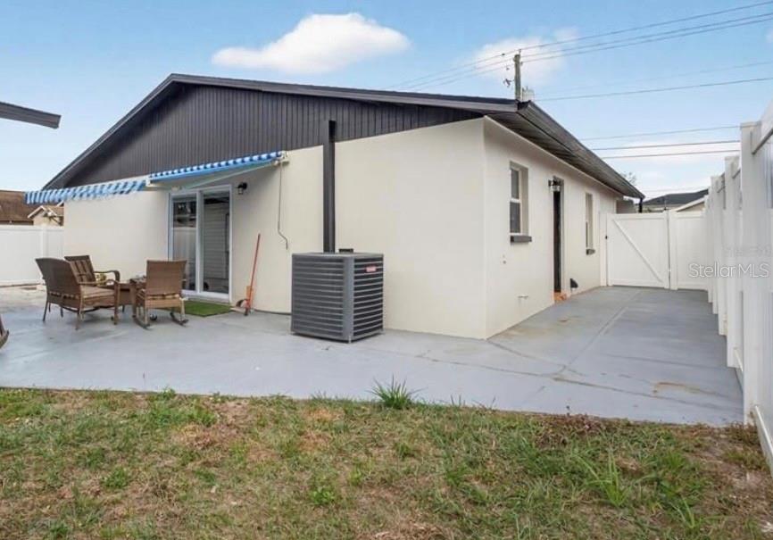 The exterior of a house features a concrete patio, an air conditioning unit, and sliding doors — 2914 W FRIERSON AVENUE UNIT C, TAMPA, FL