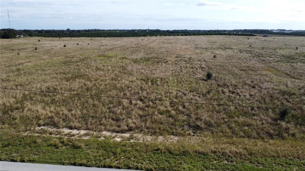 An aerial view of a large, flat, grassy field under a partly cloudy sky — 1615 EO DOUGLAS AVENUE, SEBRING, FL