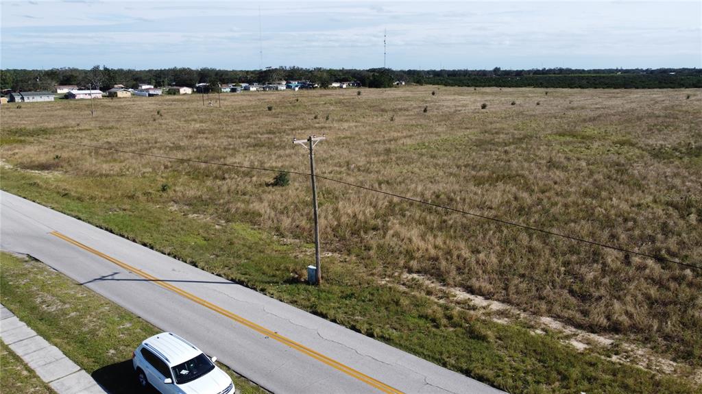 An aerial view shows a large, grassy vacant lot next to a paved road — 1615 EO DOUGLAS AVENUE, SEBRING, FL