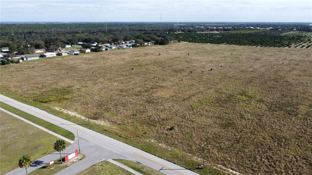 An aerial view shows a large, grassy vacant lot adjacent to a paved road — 1615 EO DOUGLAS AVENUE, SEBRING, FL