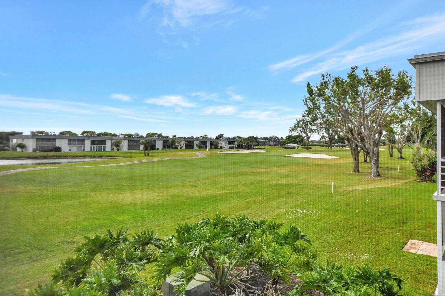 A view of a golf course fairway with sand traps and distant residential buildings — 187 Normandy D, Delray Beach FL 33484, DELRAY BEACH, FL