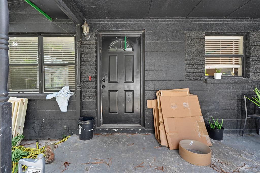 A black-painted brick exterior features a front door, two windows, and a concrete porch — 1803 E BOUGAINVILLEA AVENUE, TAMPA, FL