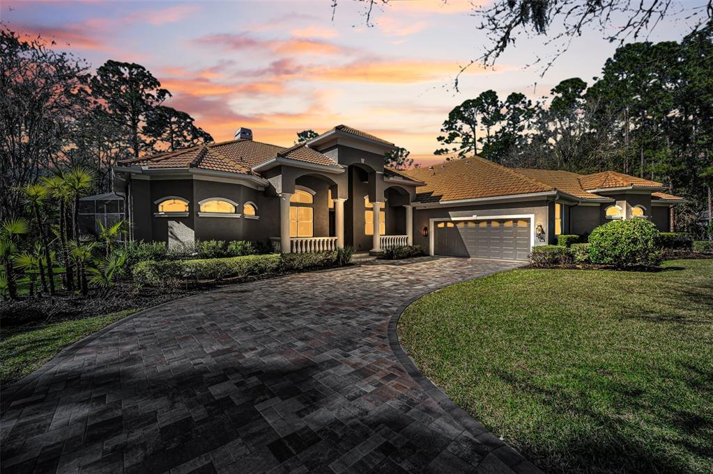 A single-story house with a paved driveway, tile roof, and arched entryway at sunset — 10709 WATULA COURT, NEW PORT RICHEY, FL