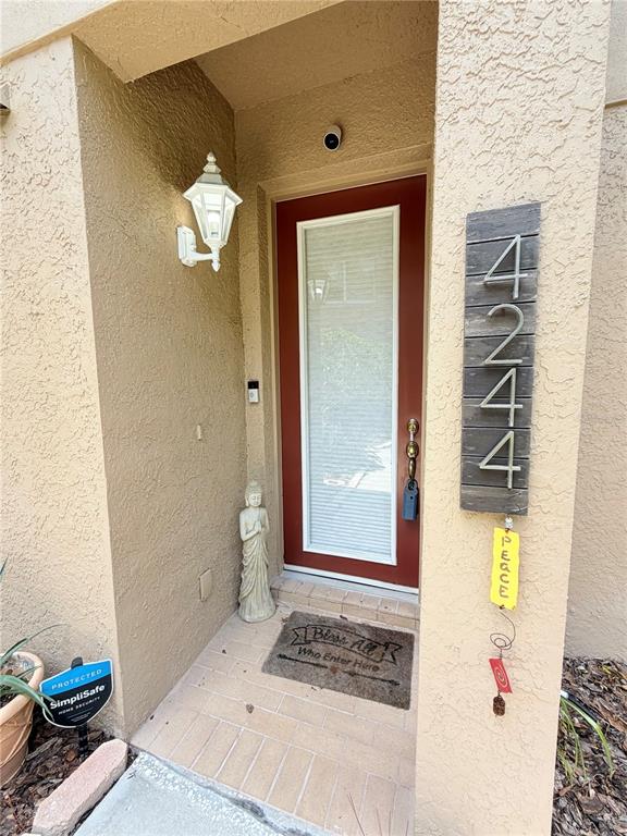 A front entryway features a red door, a house number sign, and a Buddha statue — 4244 PRESERVE PLACE, PALM HARBOR, FL