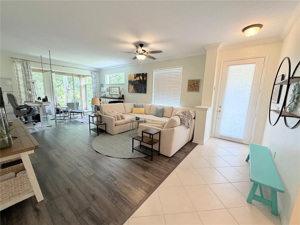 A living room features a large sectional sofa, wood-look flooring, and an adjacent tiled entryway — 4244 PRESERVE PLACE, PALM HARBOR, FL