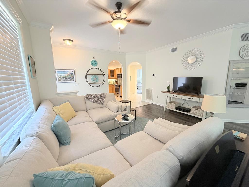 A living room features a large sectional sofa, a ceiling fan, and an arched entryway — 4244 PRESERVE PLACE, PALM HARBOR, FL